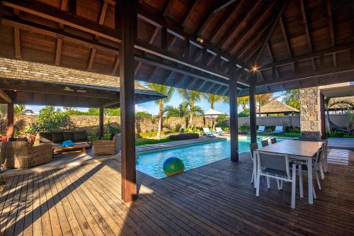 an outdoor deck with a table and chairs and a pool at Mythic Suites & Villas by MJ Holidays in Grand Gaube