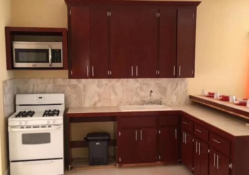 a kitchen with brown cabinets and a white stove and microwave at Mangrove Cay Sea View Villas in Behring Point
