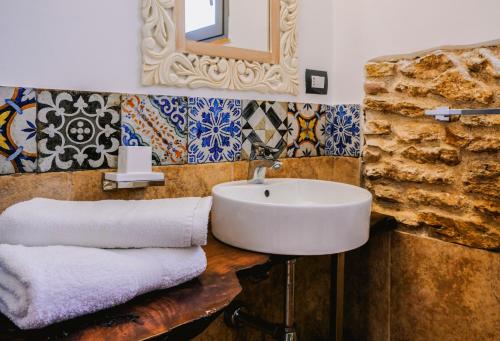 een badkamer met een wastafel, een spiegel en tegels bij Giardini Del Golfo in Balestrate