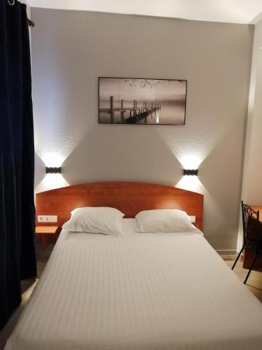 a bedroom with a large white bed with two lamps at Hotel Des Lices - Angers in Angers