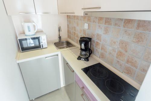 a small kitchen with a sink and a microwave at Beachfront Apartments Tivat in Tivat