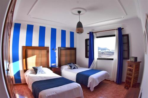 1 dormitorio con 2 camas con rayas azules y blancas en Villa Verde Mar, en Tinajo