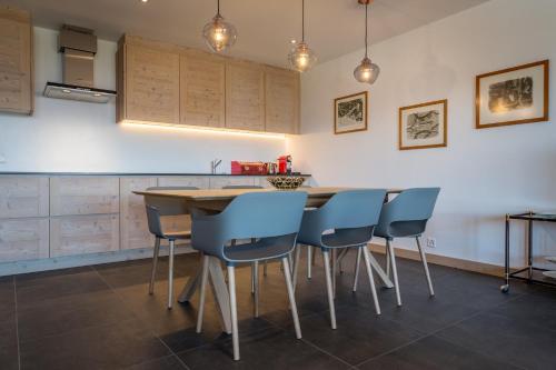 a kitchen with a wooden table and blue chairs at Apartment La Forêt 5 - Spa access - Centre Station in Nendaz