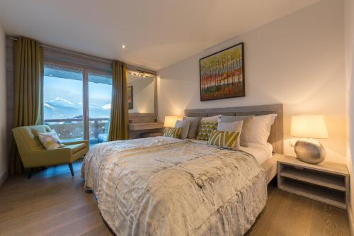 um quarto com uma cama grande, uma cadeira e uma janela em Apartment La Forêt 2 - Spa access em Nendaz