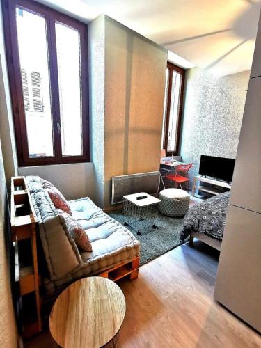 un salon avec un canapé et deux fenêtres dans l'établissement Super studio ideally located in the old town, à Annecy