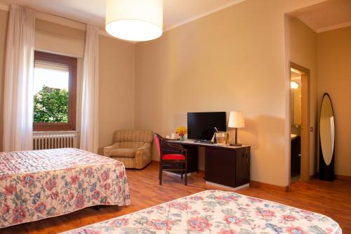 a hotel room with two beds and a desk and a chair at Hotel Villa dei Pini in San Terenziano