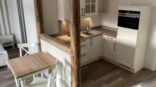 a kitchen with white cabinets and a wooden pole at Café Ilse - Ferienwohnungen in Ranis