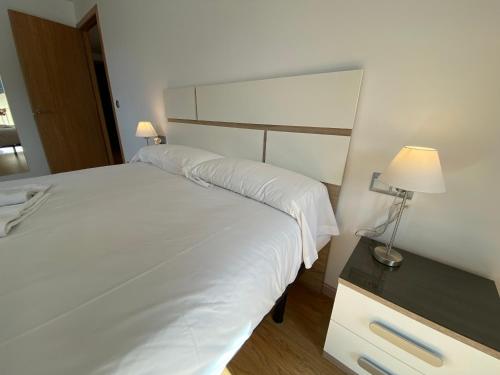 a bedroom with a large white bed and a lamp at P&C Ribasol in Arinsal