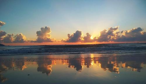 a sunset on the beach with the water and clouds at nhà Ba cơm Má in Phương Phi