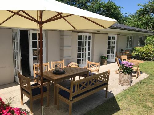 uma mesa de madeira com um guarda-chuva num pátio em Trouville Bed & Breakfast em Hornbæk