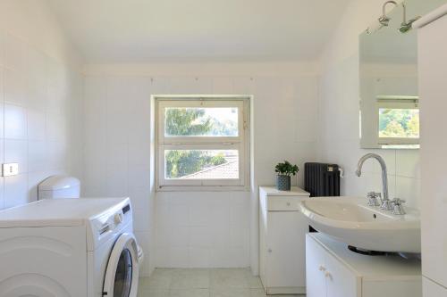 ein weißes Badezimmer mit einer Waschmaschine und einem Waschbecken in der Unterkunft Pandora Stresa - By Impero House in Stresa