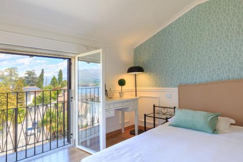 a bedroom with a bed and a desk and a balcony at Pandora Stresa - By Impero House in Stresa