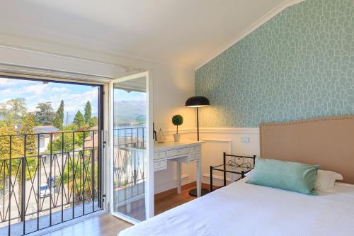 ein Schlafzimmer mit Bett und Schreibtisch und ein Balkon in der Unterkunft Pandora Stresa - By Impero House in Stresa