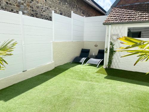 eine Terrasse mit zwei Stühlen auf dem Rasen in der Unterkunft Villa la Vie, Maison entière pour 4 personnes, avec extérieur, Tout inclus, ménage, linge, wifi in Dieppe