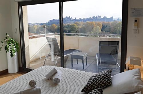 a bedroom with a bed and a view of a balcony at Les Suites du Saint Nazaire - Les Balcons de la Cité in Carcassonne