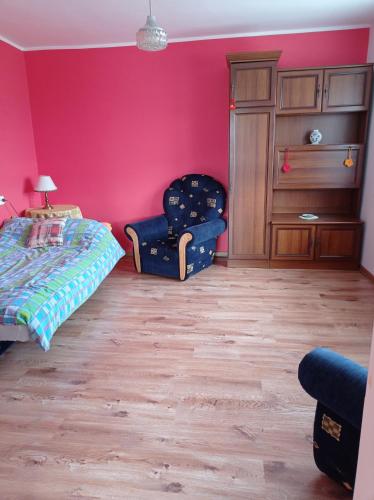 a bedroom with pink walls and a bed and a chair at Spokojny zakątek in Broda