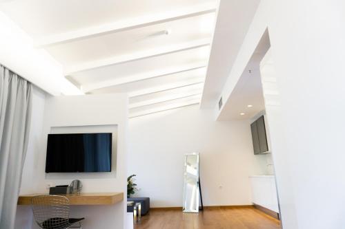 a living room with white walls and a flat screen tv at City Loft Hotel in Patra
