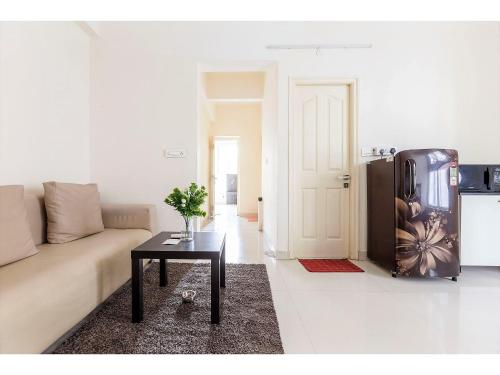 a living room with a couch and a refrigerator at BluO 1BHK Hitech City - Gym, TT, Terrace Garden, Lift in Hyderabad