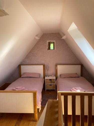 a attic bedroom with two beds and a window at The Gingerbread House Cottage in Beauficel