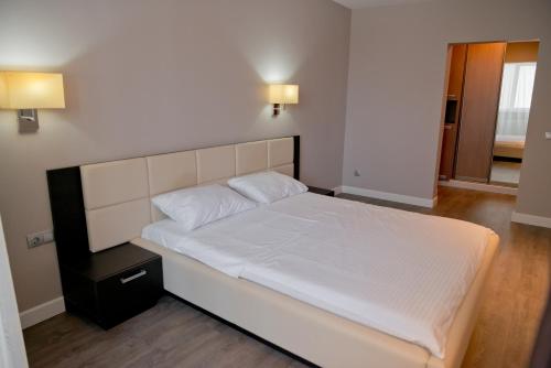 a bedroom with a white bed and a night stand at 2 bedroom apartment close to center, park and shopping center in Chişinău