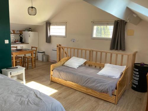 a bedroom with a wooden bed and a kitchen at Studio proche Orleans centre in Saint-Jean-le-Blanc