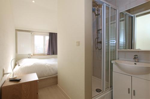 ein Bad mit einem Bett, einem Waschbecken und einer Dusche in der Unterkunft Hotel Cecil in De Panne