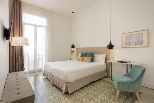 
a bedroom with a bed, chair, lamp and window at Forget Me Not in Barcelona
