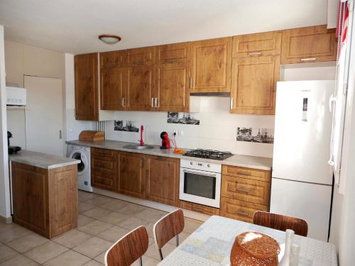 une cuisine avec des armoires en bois et un réfrigérateur blanc dans l'établissement Superbe T3 70m2, spacieux et lumineux, 4ème étage avec ascenseur, parking et terrasse, centre de Montpellier, à Montpellier