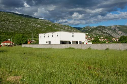 a white building in the middle of a field at Neiras Apartments Blagaj in Blagaj