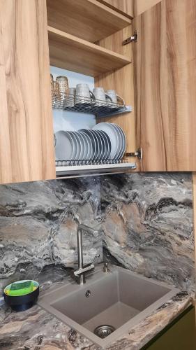 un comptoir de cuisine avec un évier et des assiettes sur les étagères dans l'établissement Апартаменти поруч із Софіївським парком Dolce Vita , "У нас є світло завжди", à Ouman