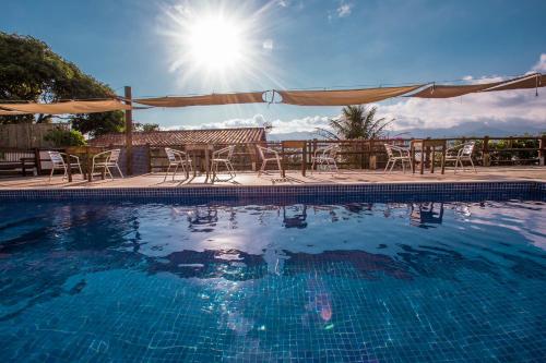una piscina con mesas, sillas y sol en Pousada Refugio da Harmonia, en Ilhabela
