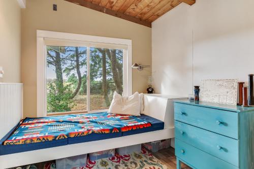 a bedroom with a window and a bed and a dresser at Dune Grass Cottage in Copalis Beach