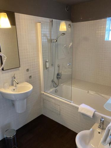 a bathroom with a shower and a sink and a tub at Hotel Georges in Pléneuf-Val-André