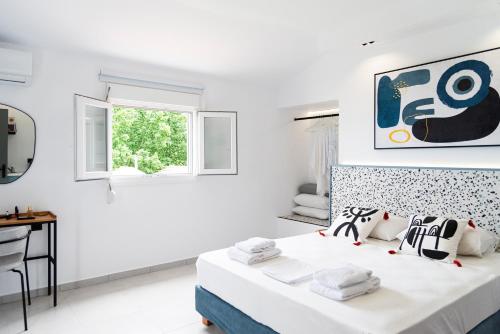 a white bedroom with a bed and a desk at Seaside Suites in Kavos