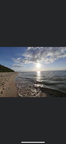 ein Bild eines Strandes mit Sonne auf dem Wasser in der Unterkunft Tadeo in Kołczewo