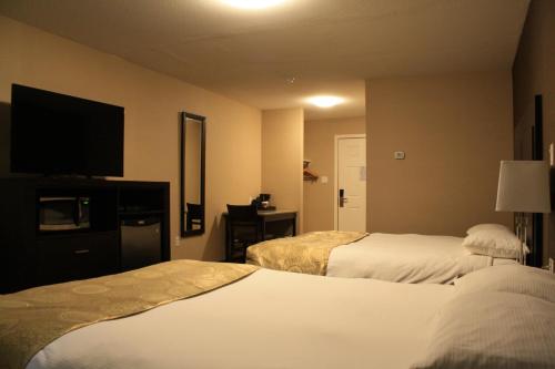 a hotel room with two beds and a flat screen tv at CHINOOK INN in Rocky Mountain House