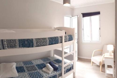 1 Schlafzimmer mit 2 Etagenbetten und einem Stuhl in der Unterkunft Casa de São Roque Açores in Ponta Delgada