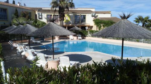 a swimming pool with chairs and umbrellas at Hotel Hélios in Cap d'Agde