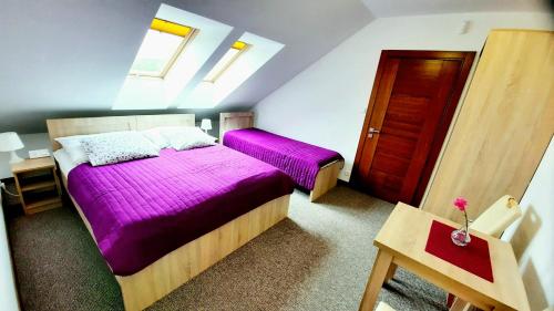 a bedroom with two beds with purple sheets and a door at Morska Fala in Jastarnia