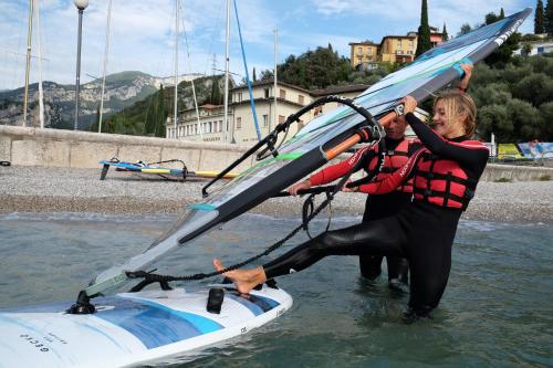 a man and woman in the water holding a surfboard at Hotel Paradiso Conca d'Oro in Nago-Torbole