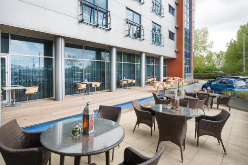 a patio with tables and chairs in front of a building at voco Reading in Reading