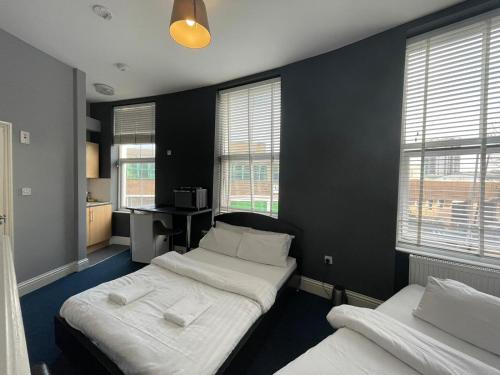 two beds in a room with black walls and windows at City Chic - King's Cross Apartments in London