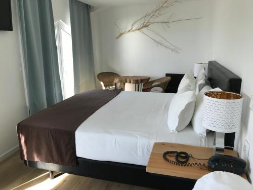 a bedroom with a large white bed and a table at Promar - Eco Beach & Spa Hotel in Maceira