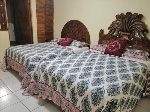 two beds in a bedroom with a bedspread at Hotel Chely in Bernal