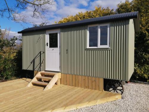 a green and white tiny house with a wooden deck at Wolstonbury Getaway in Hassocks