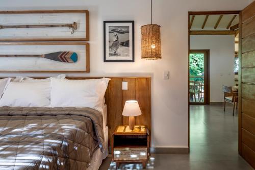 um quarto com uma cama e uma mesa com um candeeiro em Flamboyant Residence Quadrado em Trancoso