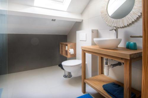uma casa de banho com um WC branco e um espelho. em B&B La maison de Régine em Jalhay