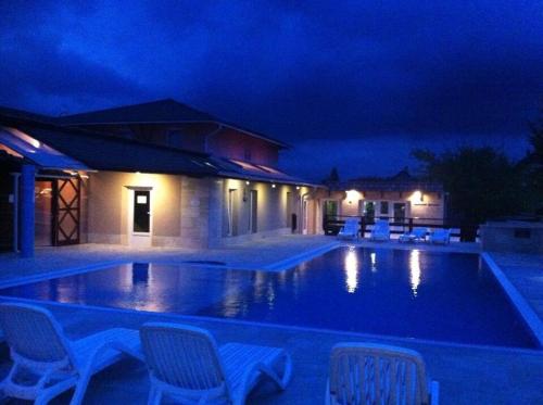a swimming pool at night with chairs around it at Bagolyvár Inárcs in Inárcs