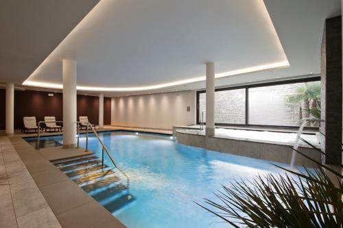 a large pool in a building with a table and chairs at Hotel Ambassador in Levico Terme