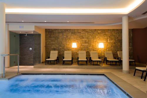 a swimming pool in a hotel lobby with chairs at Hotel Ambassador in Levico Terme